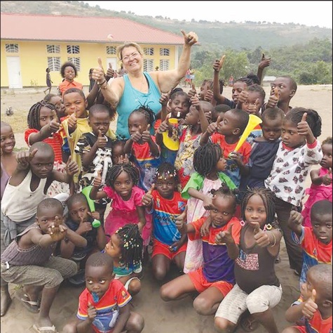 A crowd of grinning children give a big thumbs-up alongside a Kids in the Congo volunteer.